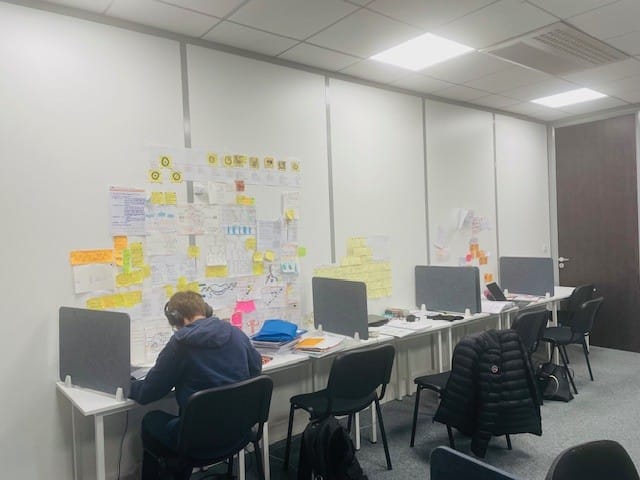 Un étudiant travaille dans une salle de cours avec un mur rempli de post-it