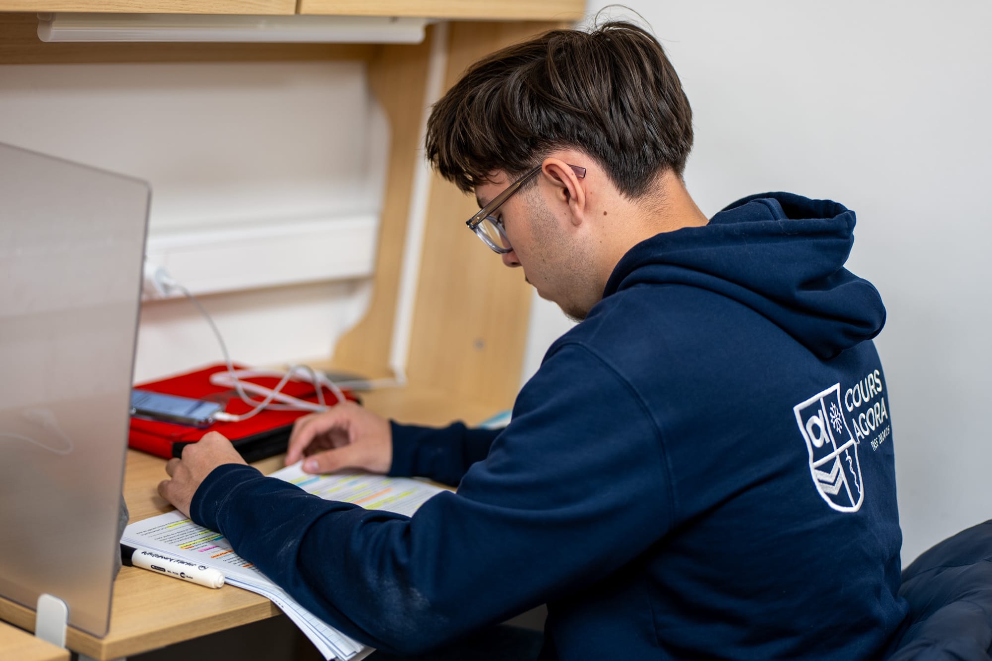 Etudiant qui révise ses cours de médecine sur son bureau avec un sweat Cours Agora