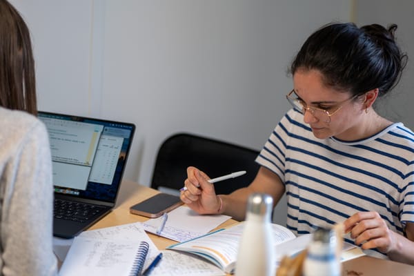Deux étudiantes révisent leurs cours de médecine, l'une sur son ordinateur, l'autre sur ses cahiers et fiches.